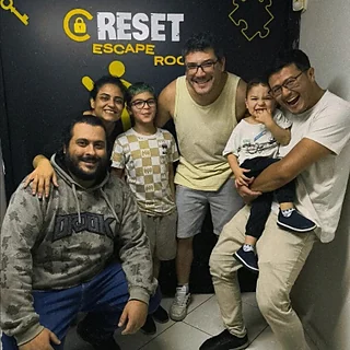 Família de sete pessoas, com crianças, comemorando na porta da Reset Escape Room